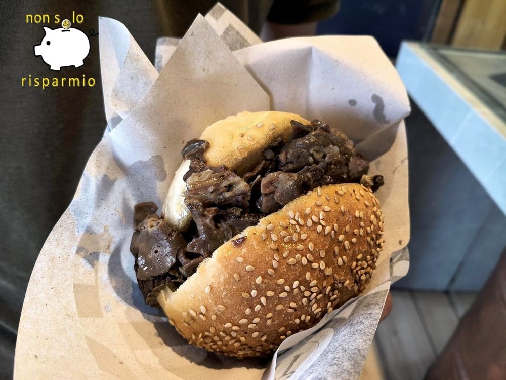 Un "pani ca meusa" servito in carta alimentare: panino morbido al sesamo ben farcito con fettine sottili di milza e frattaglie cotte nello strutto