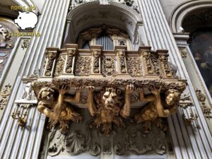 Pregevole cantoria lignea dorata d'epoca barocca sostenuta da imponenti figure scolpite di atlanti e una testa di leone, posta sotto le canne dell'organo di una chiesa