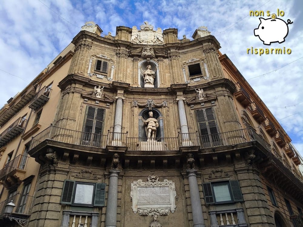 Facciata barocca concava di uno dei Quattro Canti a Palermo, con colonne, nicchie contenenti statue reali e della patrona, targa commemorativa e stemma in cima.