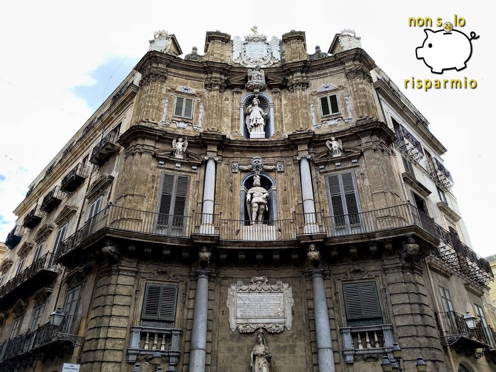 Inquadratura frontale e simmetrica della maestosa facciata barocca concava dei Quattro Canti a Palermo con statue, balconi e stemma d'atrio supremo.